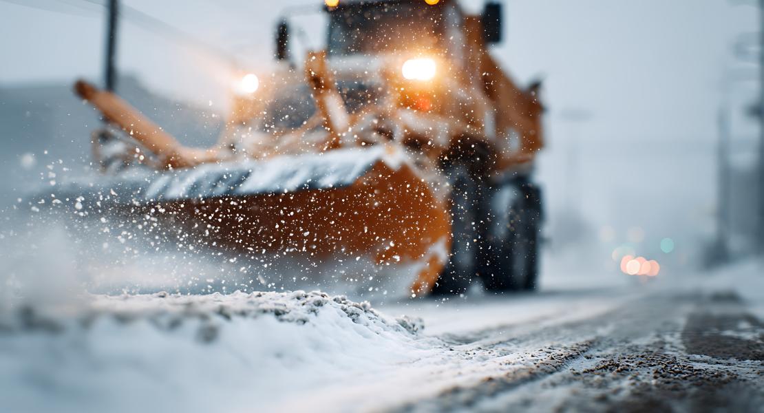 Snow plow driving down snowy road